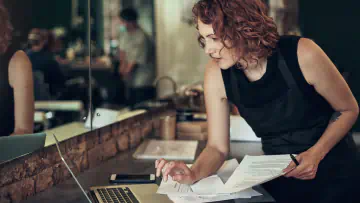 Woman takes notes and uses laptop