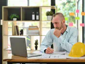 Man sits at a desk and looks at a laptop